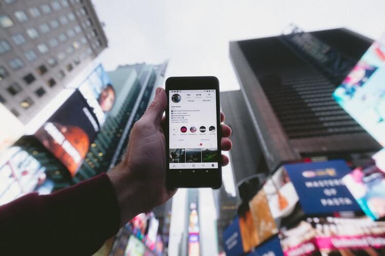 A man holding a black mobile phone while on Instagram.