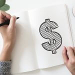 A woman drawing the dollar sign on her notebook.
