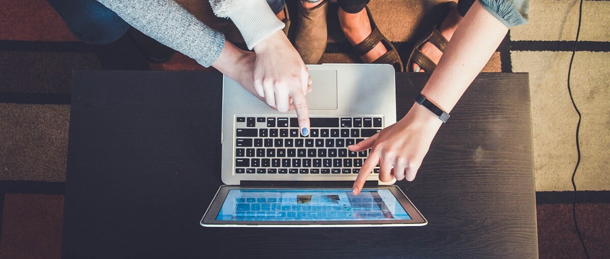 Young people pointing at a certain element on the screen of a laptop.