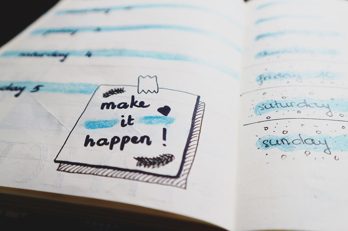 Calendar on a notebook with a message that reads Make It Happen.
