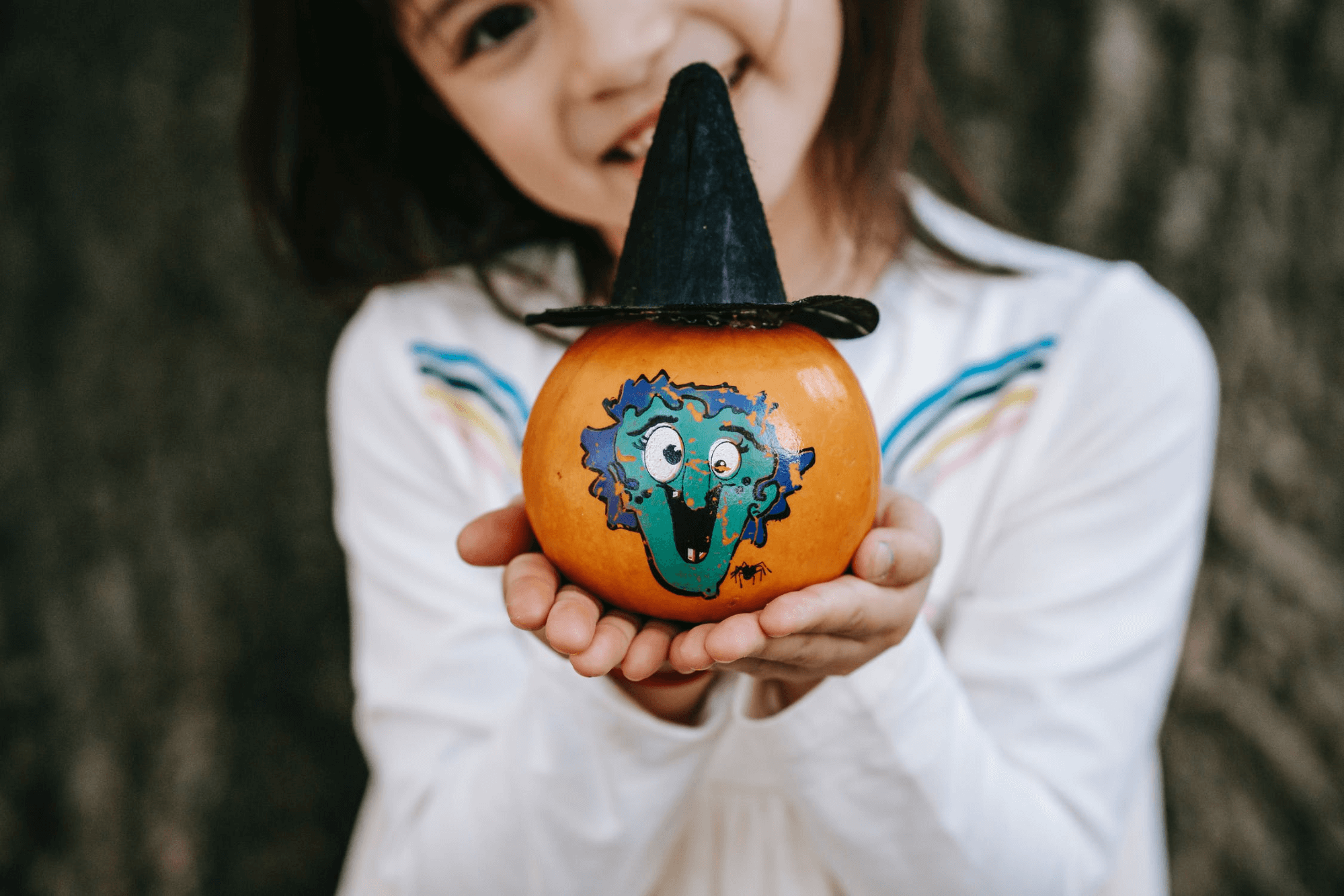 picture showing a girl offering a small painted pumpkin on Thanksgiving day