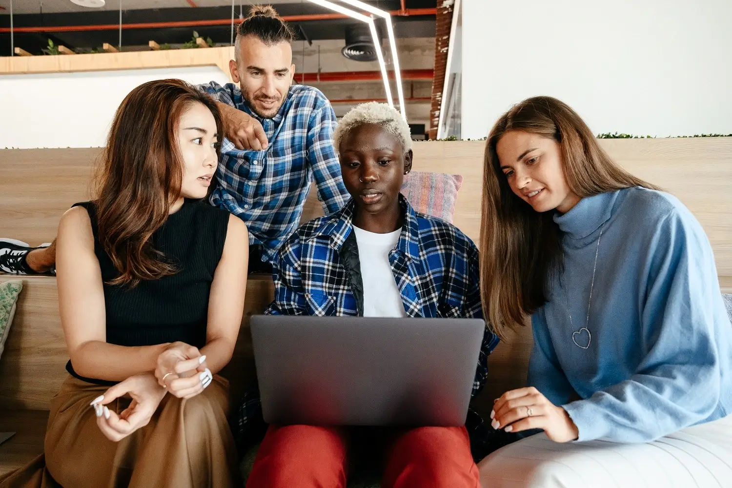 group of young people gathered around laptop