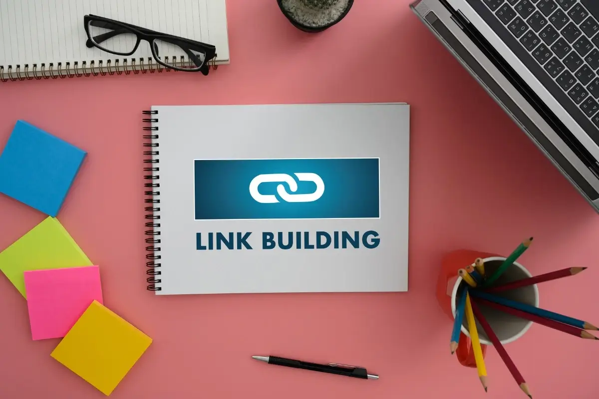 Link building, how to build links for your website. With the image showing a notebook and a pen for strategizing link buidling.