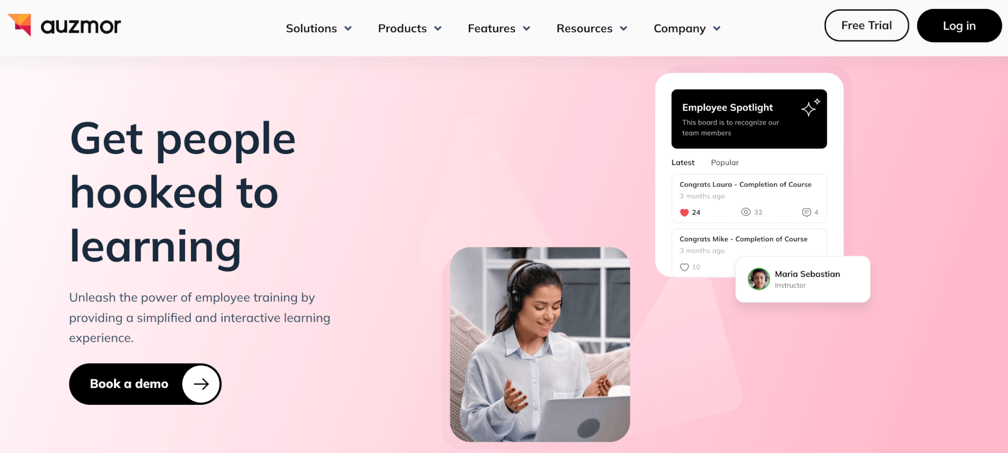 an image of Auzmor Learn's landing page showing a woman with laptop and headphones in pink background