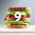 An image showing a tall sandwich in a grey background featuring the number 9.