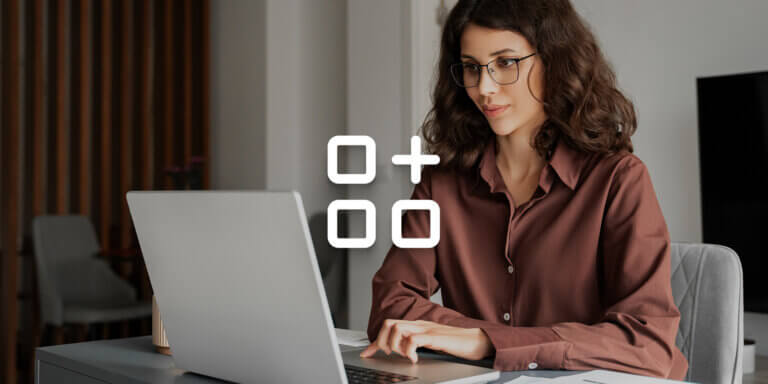 An image showing a woman with wavy hair and glasses useing a laptop.