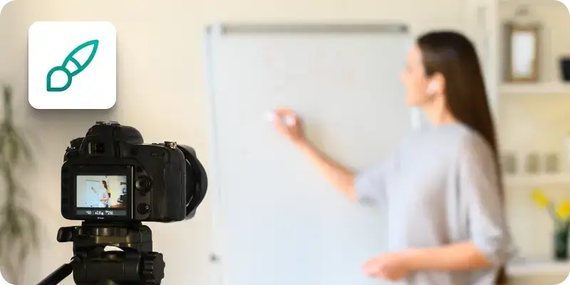 An image showing a woman writing something on a whiteboard while recording a video.