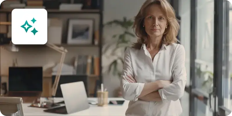 An image showing a woman with crossed arms standing next to her office desk.