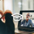 An image showing a man wearing glasses talking to another person via a camera on a laptop screen.
