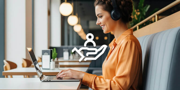 An image showing a woman wearing headphones and an orange shirt using a laptop at a cafe.
