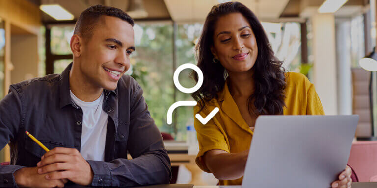 A smiling man and woman looking at a laptop screen