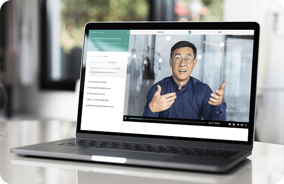 Laptop on a desk showing a video lesson with an instructor speaking on screen.