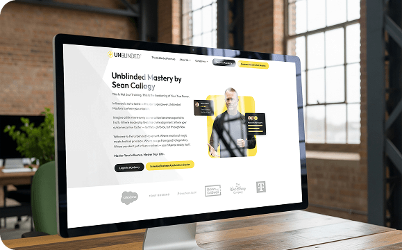 Unblinded Mastery coaching academy website shown on a desktop monitor.