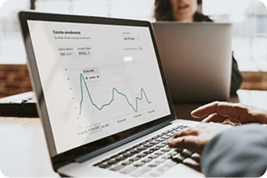 Hands on a laptop showing charts and analytics on screen.