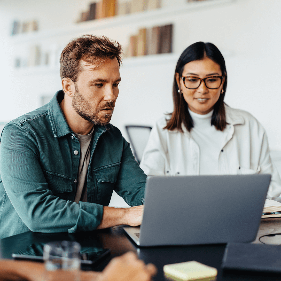 Two business professionals collaborating while reviewing information on a laptop