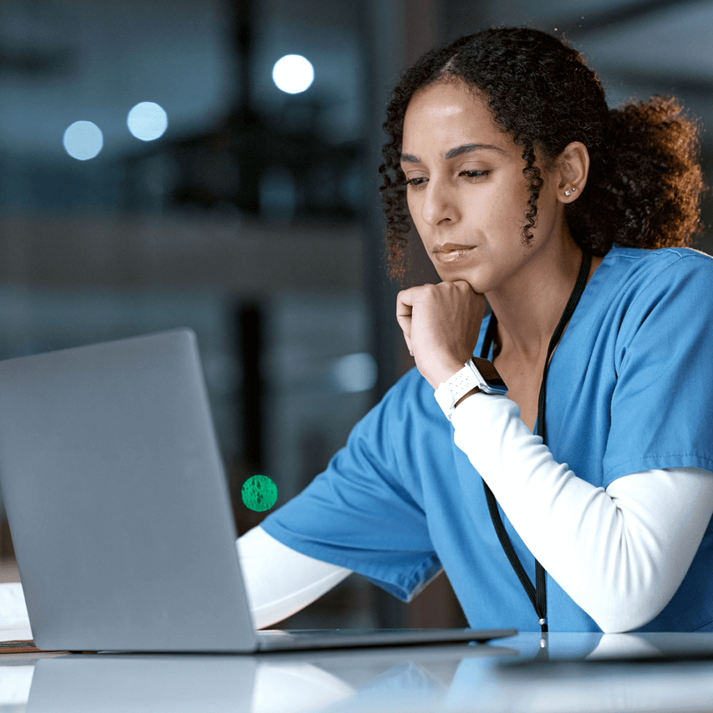 A woman in health uniform looking at a laptop screen.