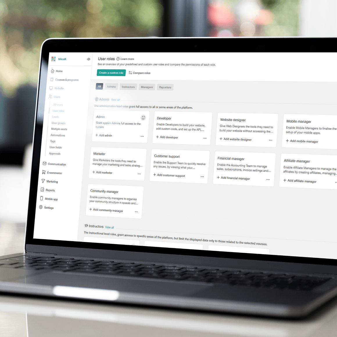 Admin dashboard on a laptop showing role-based access controls inside LearnWorlds.