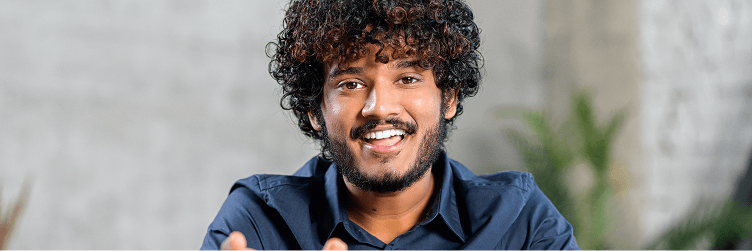 A man with curly hair and a blue shirt talking.