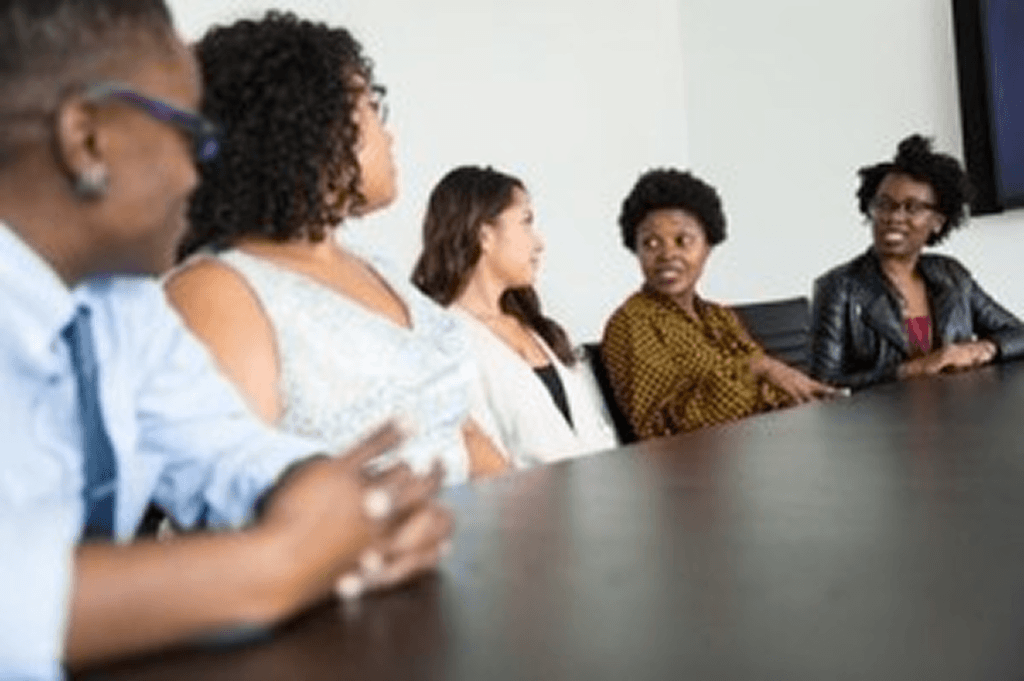 Group of professionals seated around a conference table discussing ideas during a business workshop.