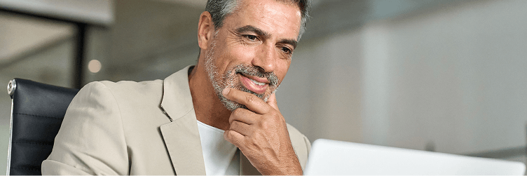 An image of a man looking at a laptop screen at the office. 