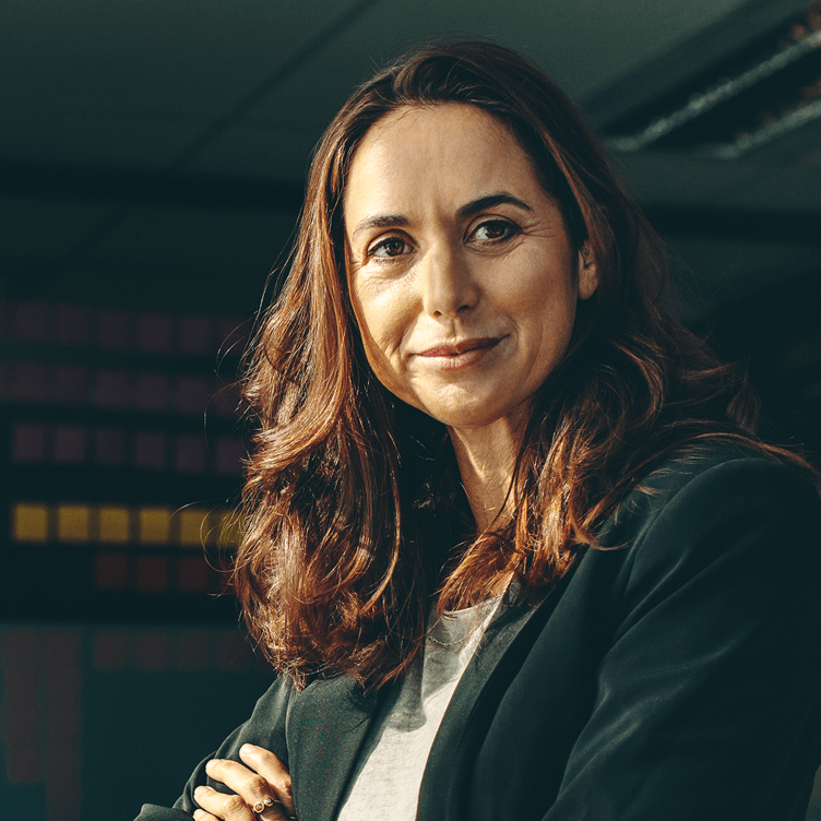 Mujer profesional con los brazos cruzados sonriendo a la cámara.